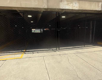 parking-garage-chain-link-fence Black chain link security fence installed at a parking garage entrance for restricted access.